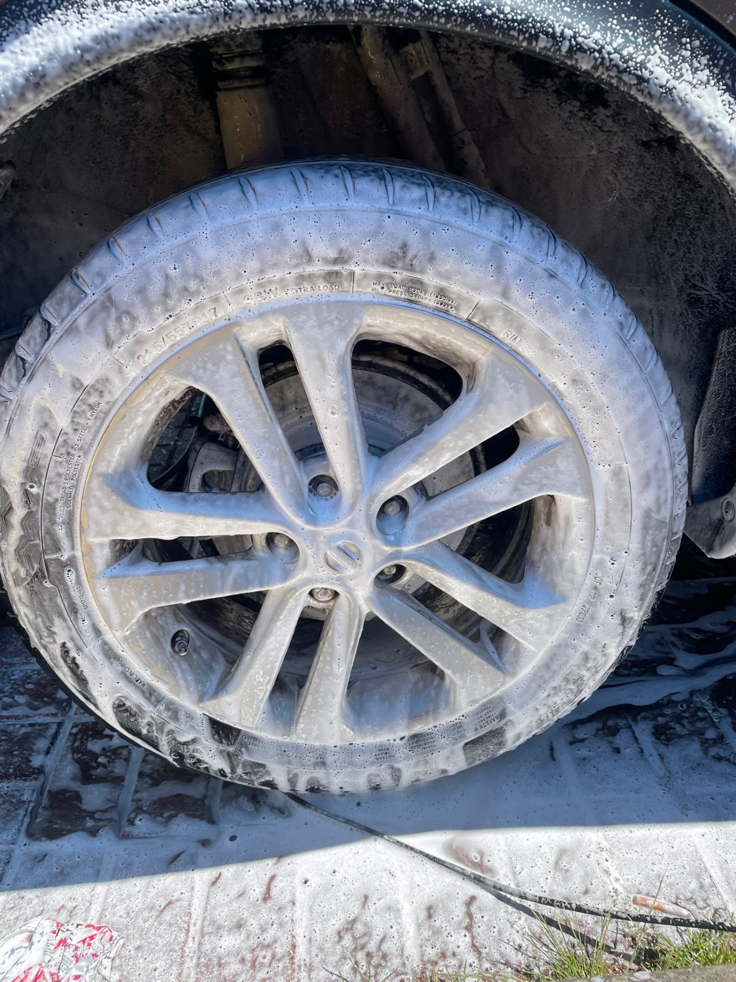Alloy wheel covered in snow foam during a wash